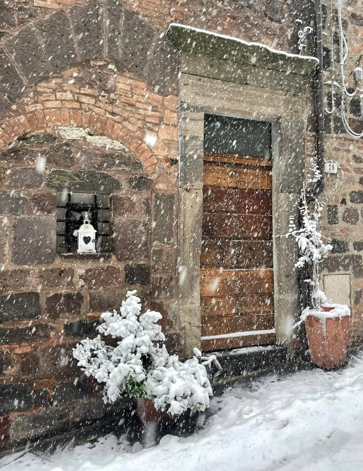 Portone in legno e muro in pietra del borgo sotto la neve