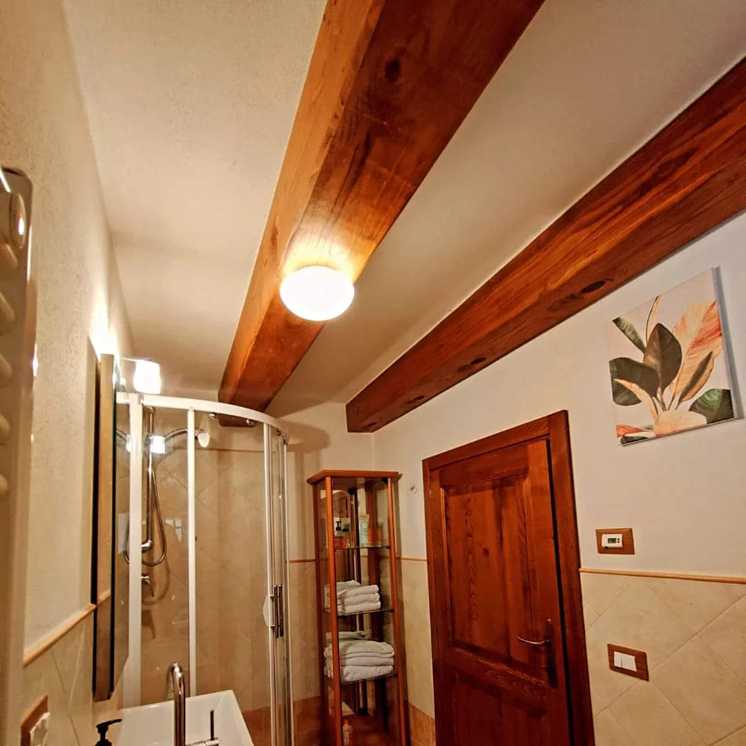 Bagno con travi in legno e scaffale con asciugamani